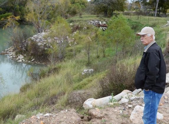 Curtis Afflerbach looks toward the Guadalupe River that deposited a large metal tank onto land north of State Highway 72 in Cuero.