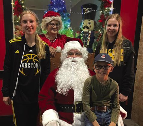 Rylie, Sydnie, and Liam Krueger take a picture with Santa Claus.