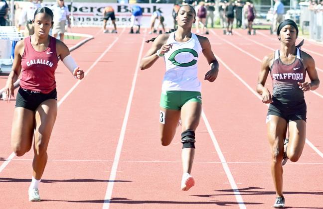 Cuero’s Emeree Dasilva, center, crosses the finish line i the 100-meter dash in third place. However, she was awarded second place after Corpus Christi Calallen’s Aubrey Navarro, left, impeded Dasilva at the start of the race. PHOTO BY COY SLAVIK/THE CUERO RECORD