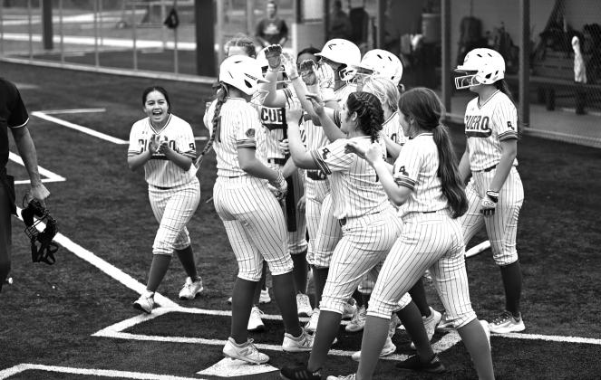 The team gathers around Audrey Kremling at home plate to celebrate her home run. She had three homers in the tournament. Kremling was also selected as the All Tournament Player.